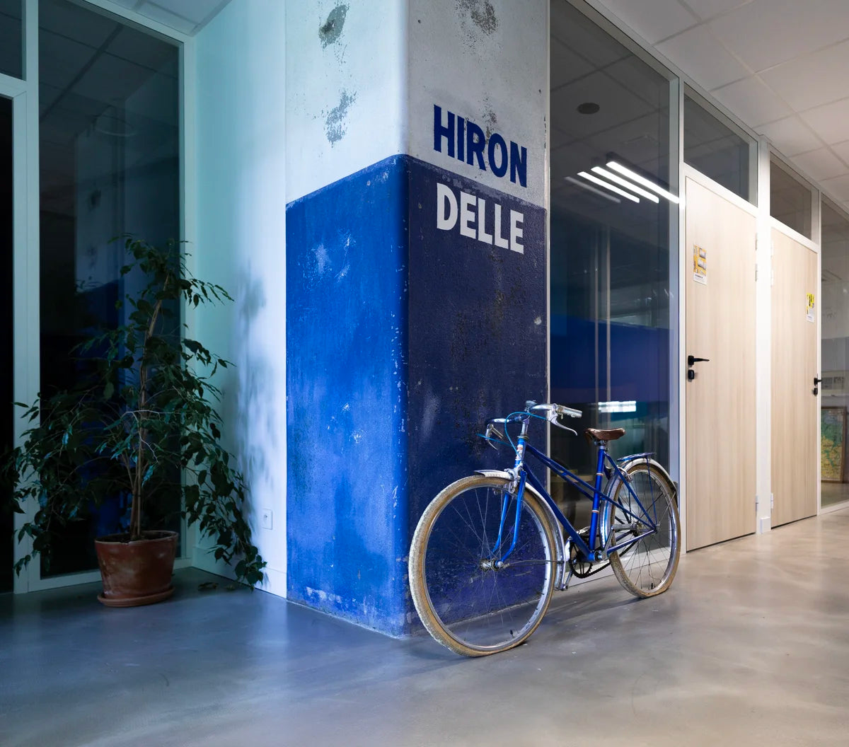 Hall de WIDE Fauriel : pilier bleu marqué Hirondelle et vélo Manufrance devant les bureaux vitrés