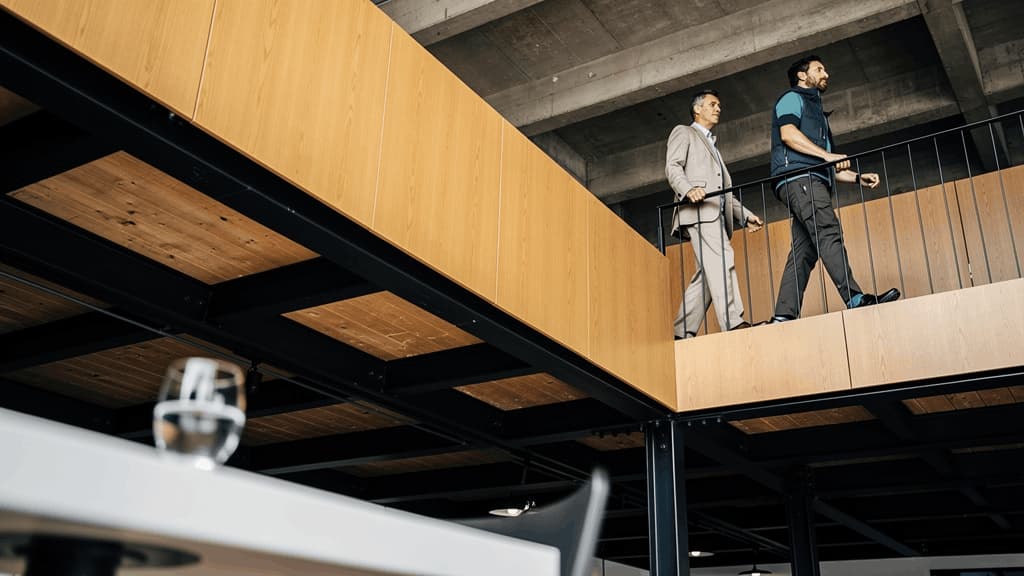 Passerelle intérieure reliant les espaces de travail d'un campus de bureaux avec architecture contemporaine et environnement professionnel.