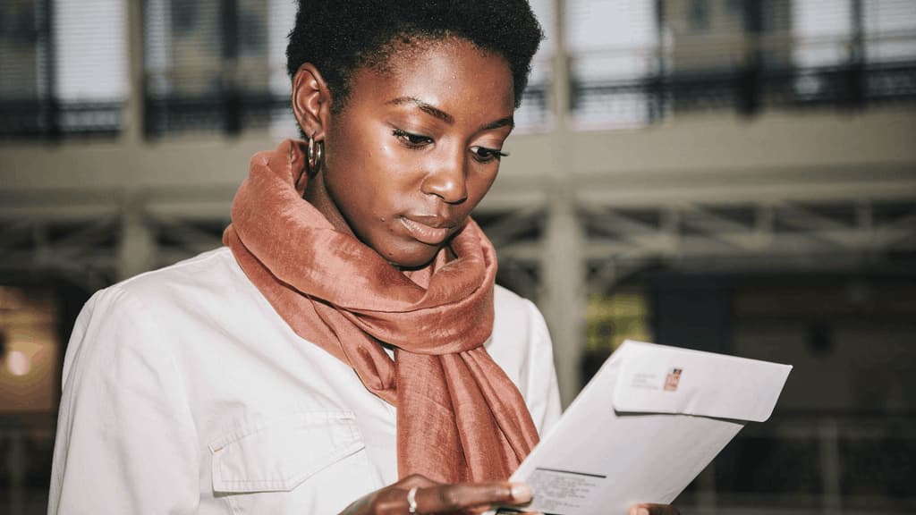 Femme consultant un courrier professionnel illustrant la réception d'une attestation de domiciliation ou de documents administratifs liés à la domiciliation d'entreprise.